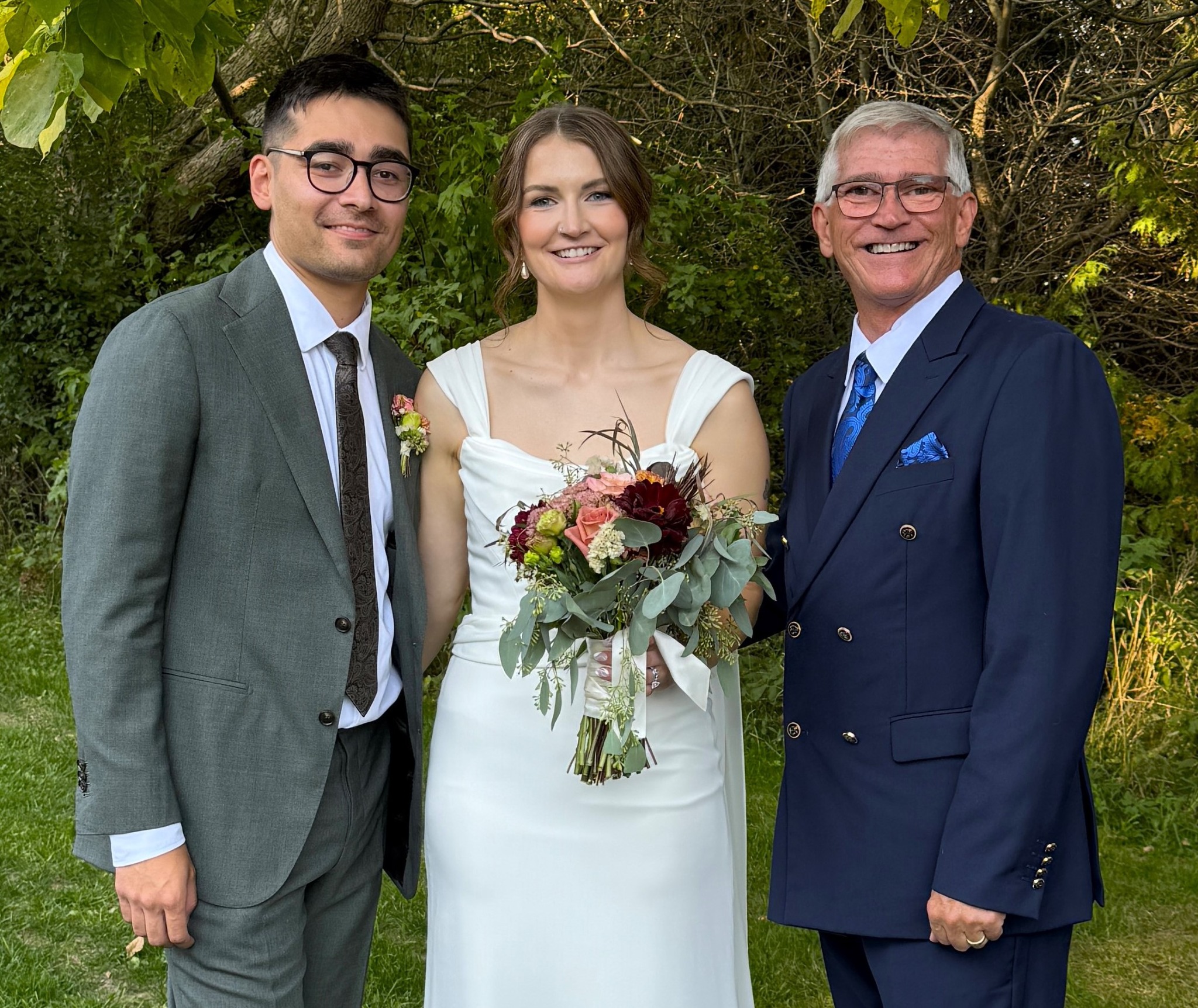 Jeff Sager smiling with newlyweds in a wooded outdoor setting